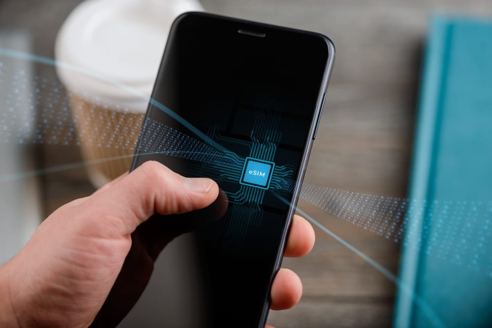 Hand,Holding,A,Smart,Phone,With,E-sim,Chip,,Electronic,Concept. esim