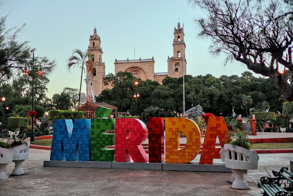 Blick auf den farbenfrohen Merida-Schriftzug mit Kathedrale Mérida Catedral de San Ildefonso im Hintergrund im mexikanischen Bundesstaat Yucatan.