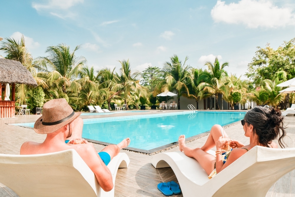 Pärchen sitzt im Sommerurlaub am Pool