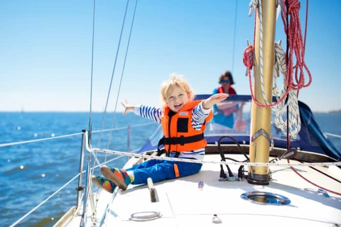 Kind sitzt gut gelaunt auf einer Yacht