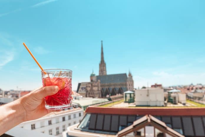 Hand,With,Glass,Of,Cocktail,With,Vienna,Cityscape,View,At Rooftopbar in Wien