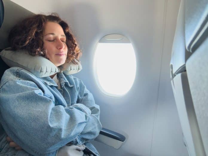 Frau sitzt mit Nackenkissen in Flugzeug