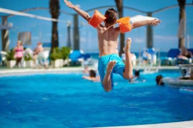 Junge springt mit Schwimmhilfe in den Pool