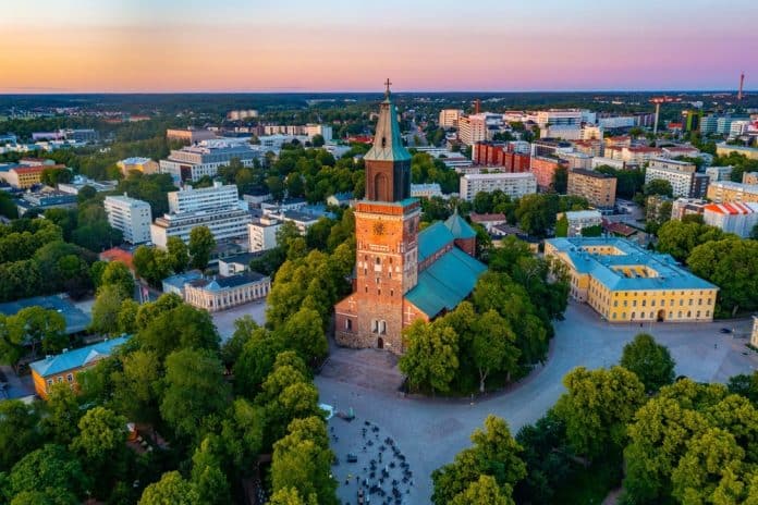 Sunset,View,Of,The,Cathedral,In,Turku,,Finland. Luftaufnahme der Kathedrale von Turku, einer der wichtigsten Sehenswürdigkeiten der Stadt, umgeben von Bäumen und städtischen Gebäuden bei Sonnenuntergang, mit Schatten, die das warme Sonnenlicht wirft, und einem klaren Himmel im Hintergrund.