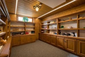 Ein Raum mit holzvertäfelten Wänden, Teppichboden und Holzregalen, die mit allerlei Kinderspielzeug gefüllt sind.