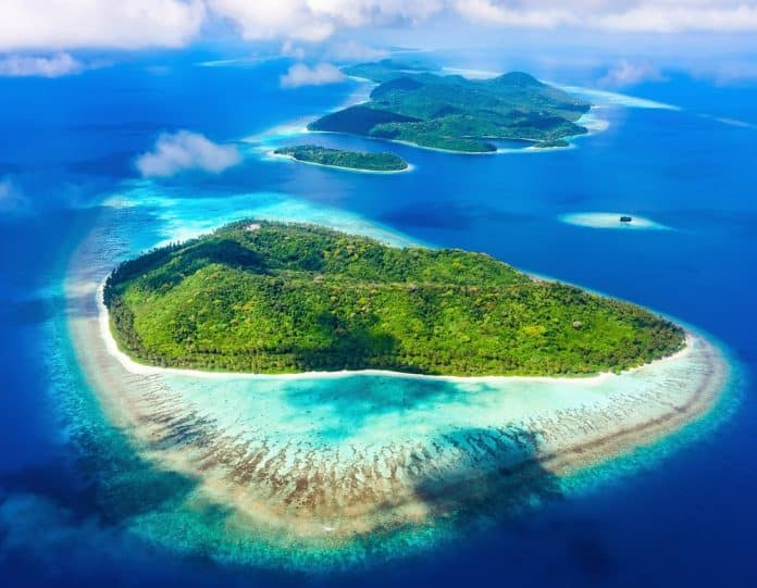 A,Breathtaking,Tropical,Island,Chain,In,Fiji,,South,Pacific,,Featuring Luftaufnahme von üppig grünen tropischen Inseln, umgeben von leuchtend türkisfarbenen Korallenriffen im tiefblauen Ozean.